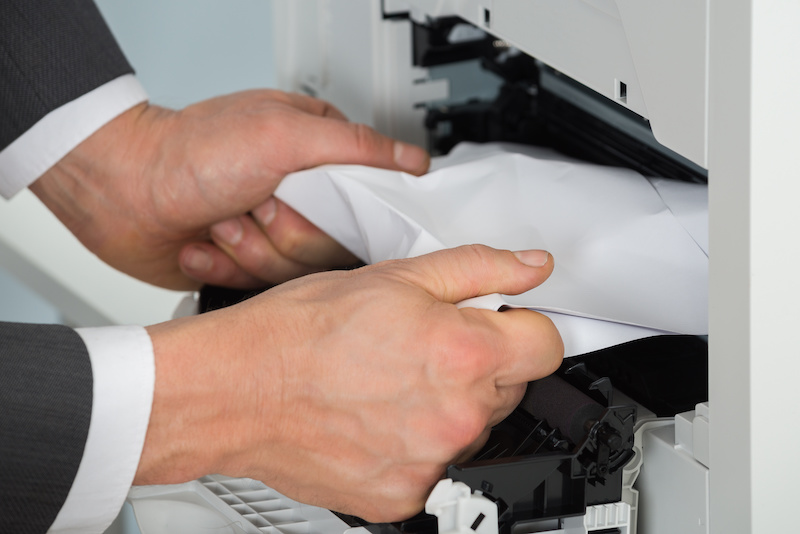 Businessman Removing Paper Stuck In Printer At Office